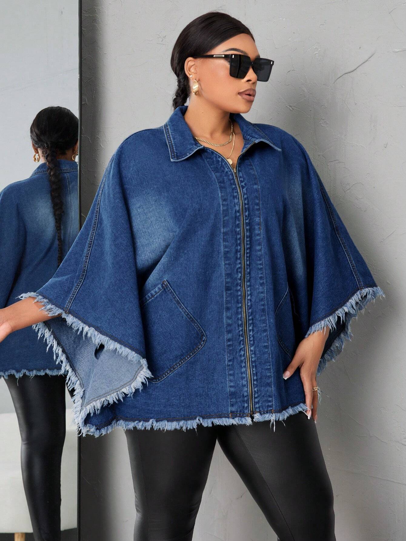 Woman wearing a blue denim poncho against a gray wall.