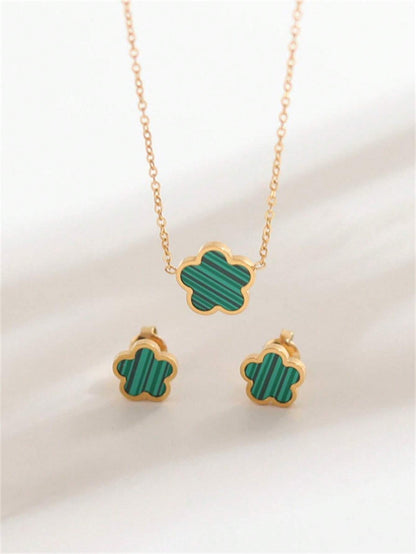 Gold necklace and earrings with green clover-shaped pendants on a white background