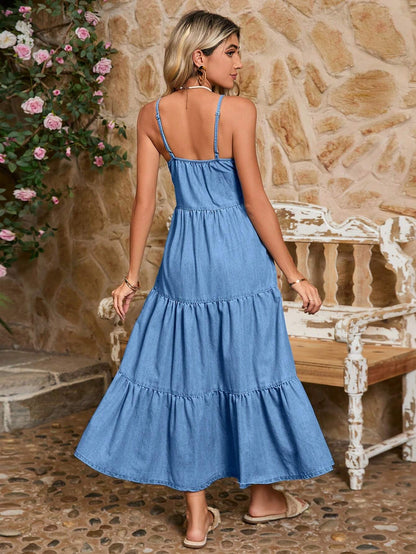 Woman wearing a blue dress standing in front of a stone wall with floral decorations.