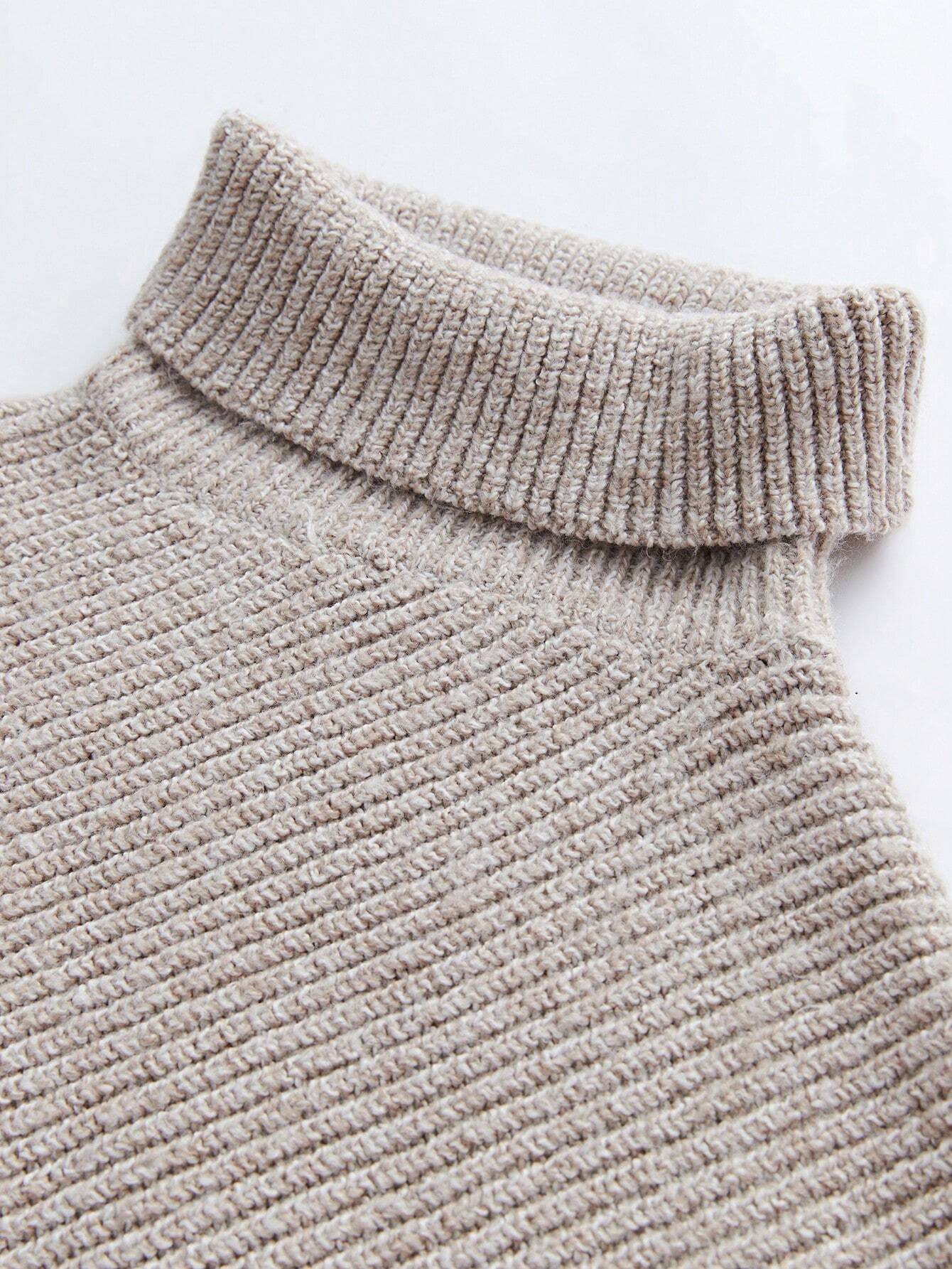Close-up of a textured beige sweater with a high collar on a light gray background