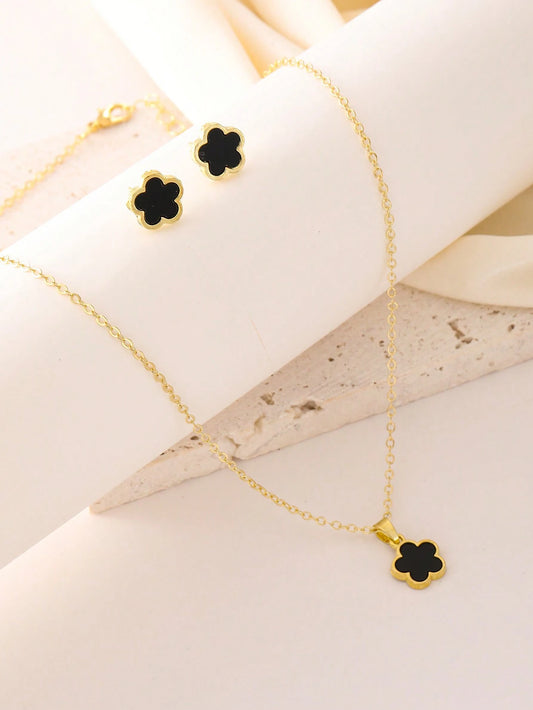 Gold necklace with black clover pendants on a white fabric background