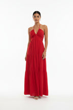 Red halter neck dress worn by a person against a white wall.