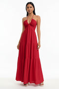 Red halter neck dress worn by a person against a white brick wall.