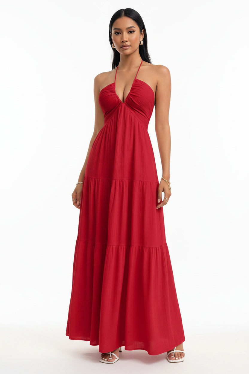 Red halter neck dress worn by a person against a white brick wall.