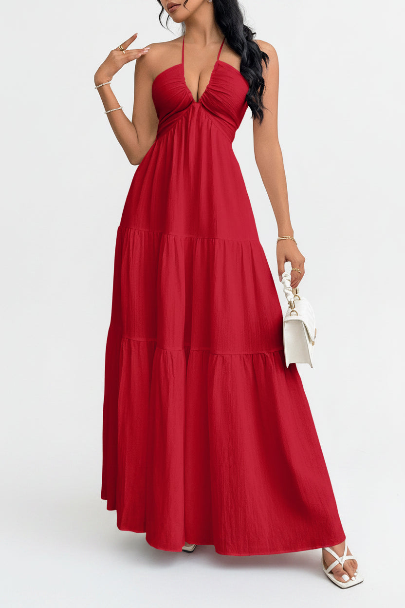 Woman wearing a red halter neck dress against a white wall.