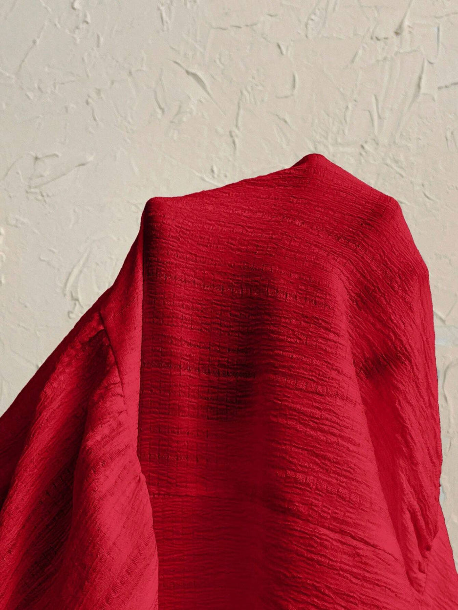 Red fabric draped over a textured beige surface