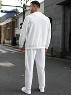 Person wearing a white tracksuit standing on a street.
