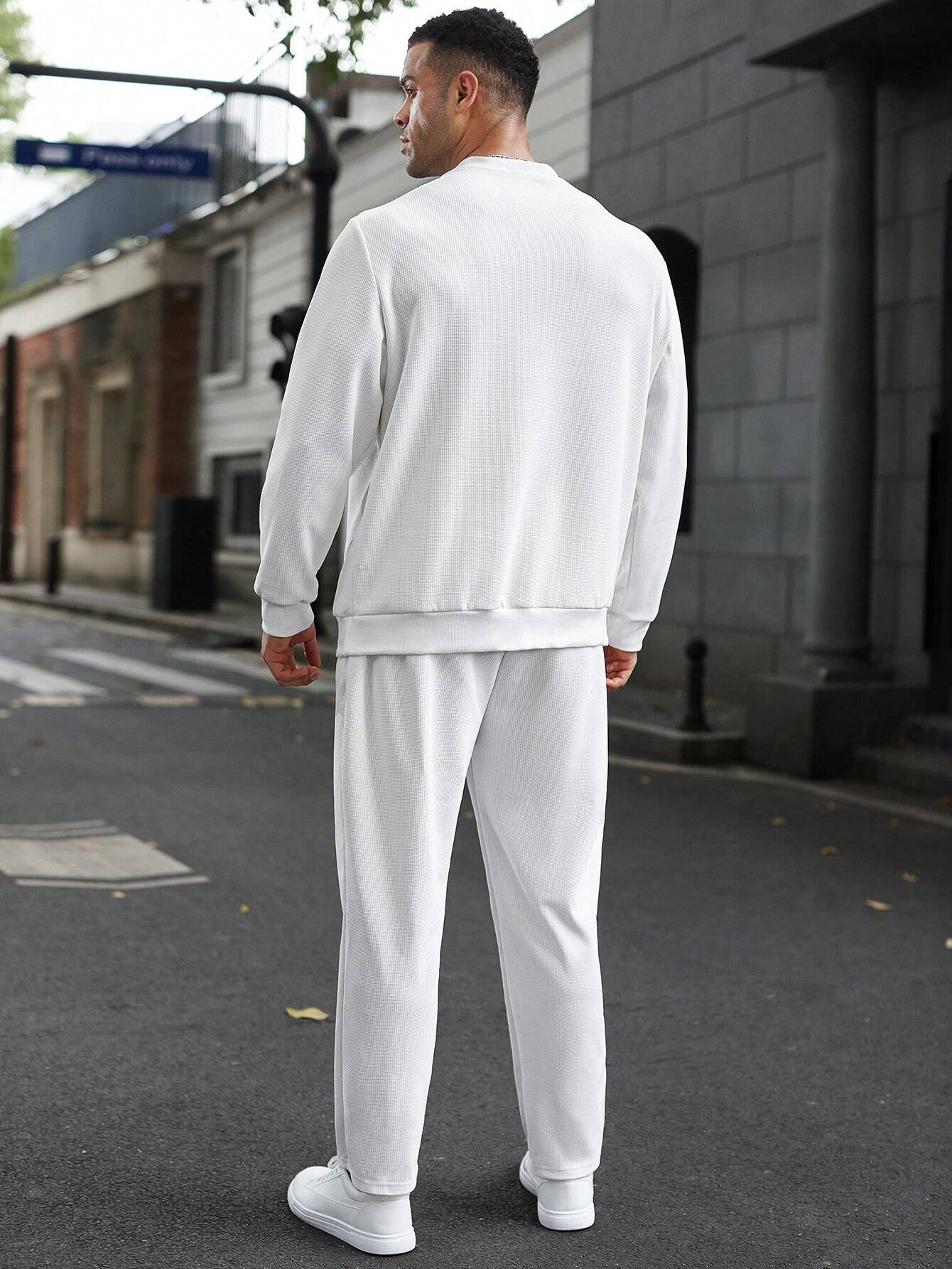 Person wearing a white tracksuit standing on a street.