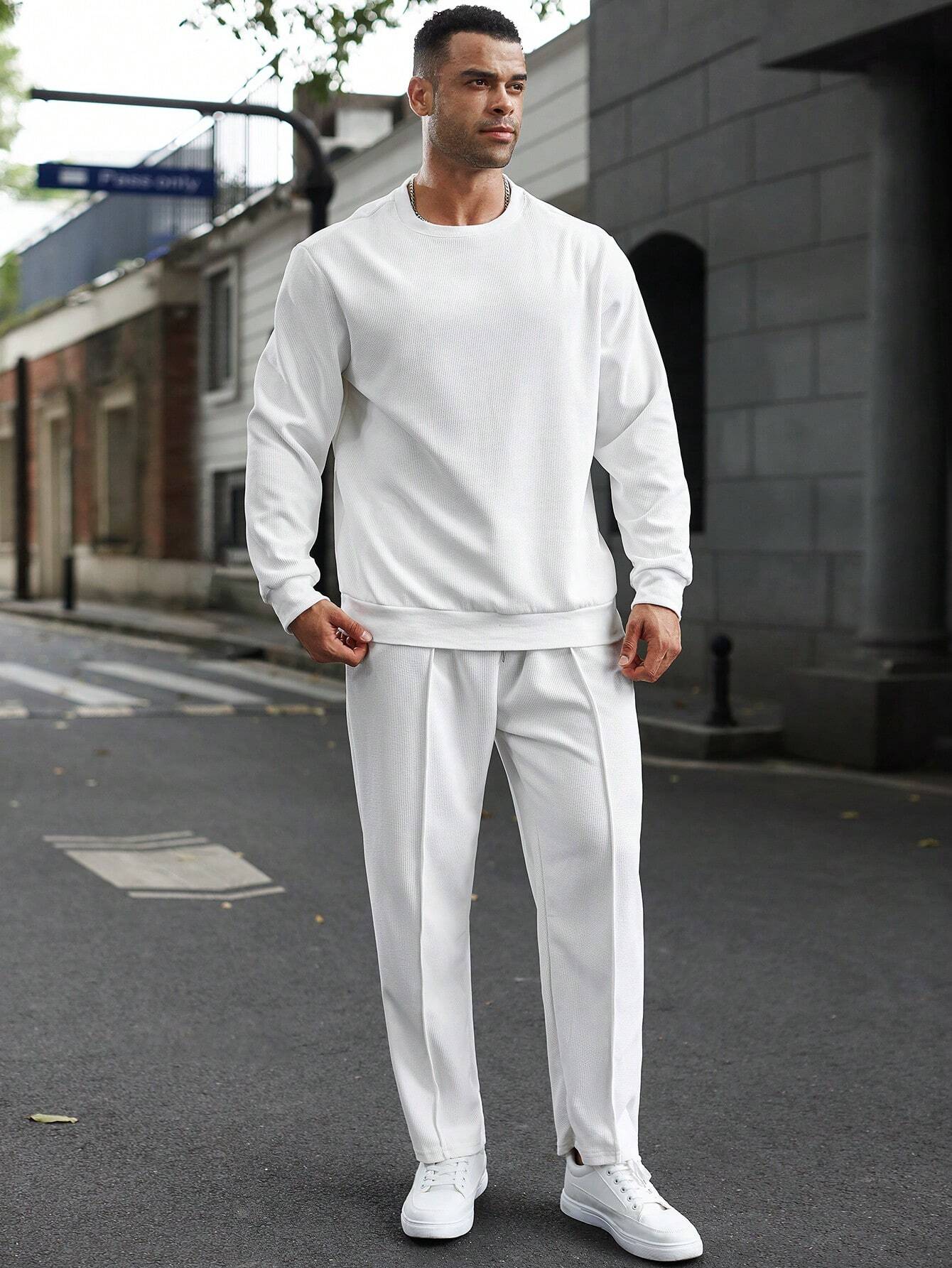 Man wearing a white outfit standing on a street.