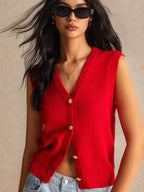 Woman wearing a red sleeveless top with gold buttons against a beige background