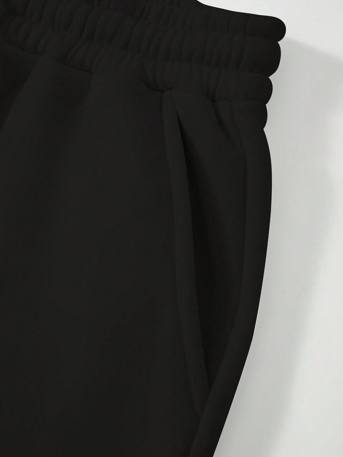Close-up of black pants with a white background