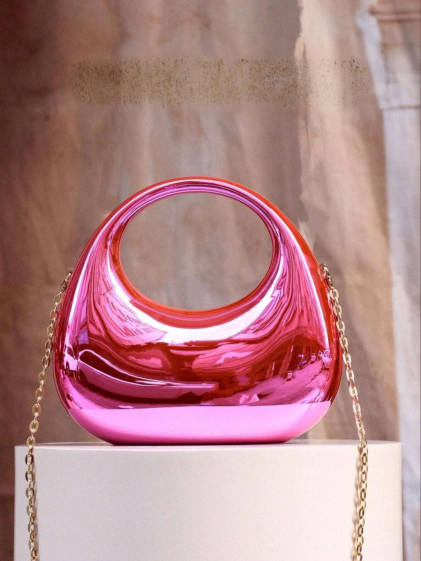 Shiny pink handbag with gold chain on a neutral background