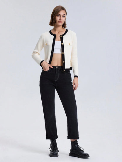 Woman wearing a white cardigan, black pants, and black boots on a light gray background