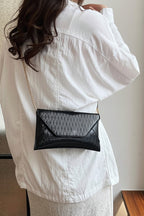 Person wearing a black mesh handbag over their shoulder against a neutral background