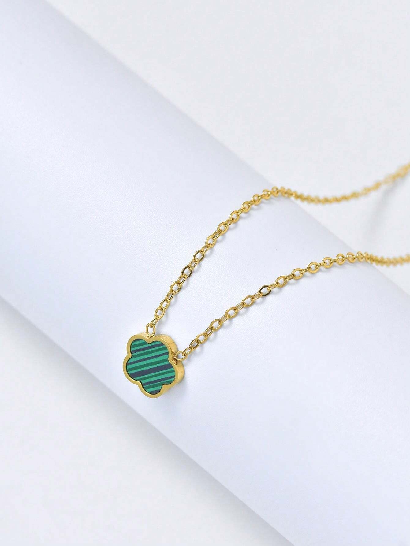 Gold necklace with a green pendant on a white background