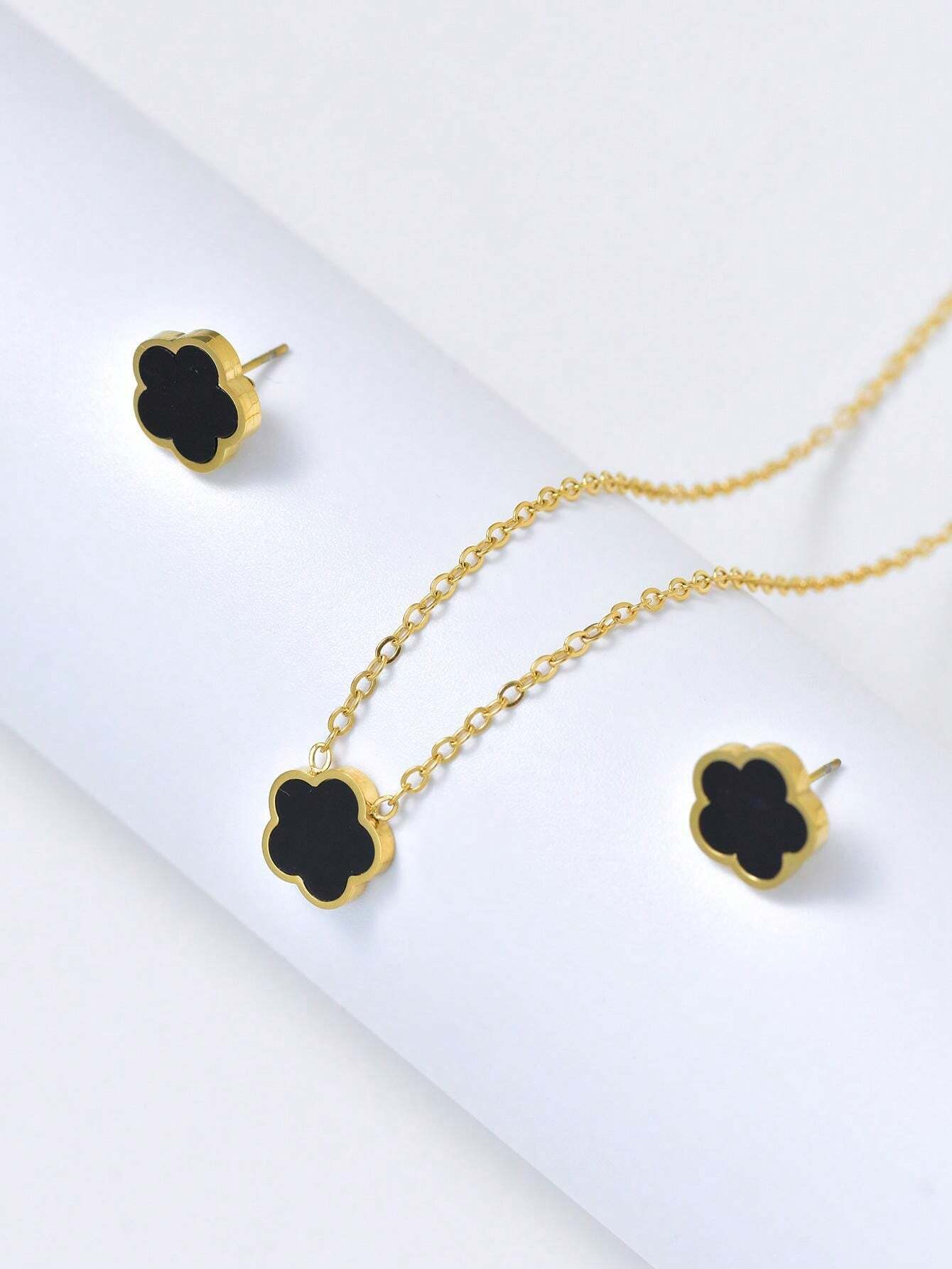 Gold necklace with black clover-shaped pendants on a white background