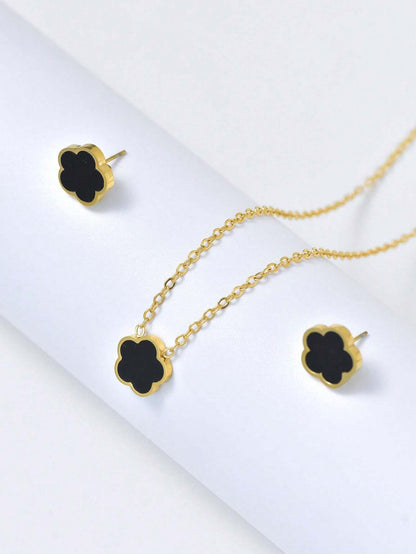 Gold necklace with black clover-shaped pendants on a white background