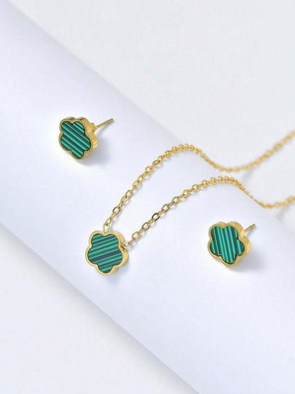 Gold necklace with green clover-shaped pendants on a white background
