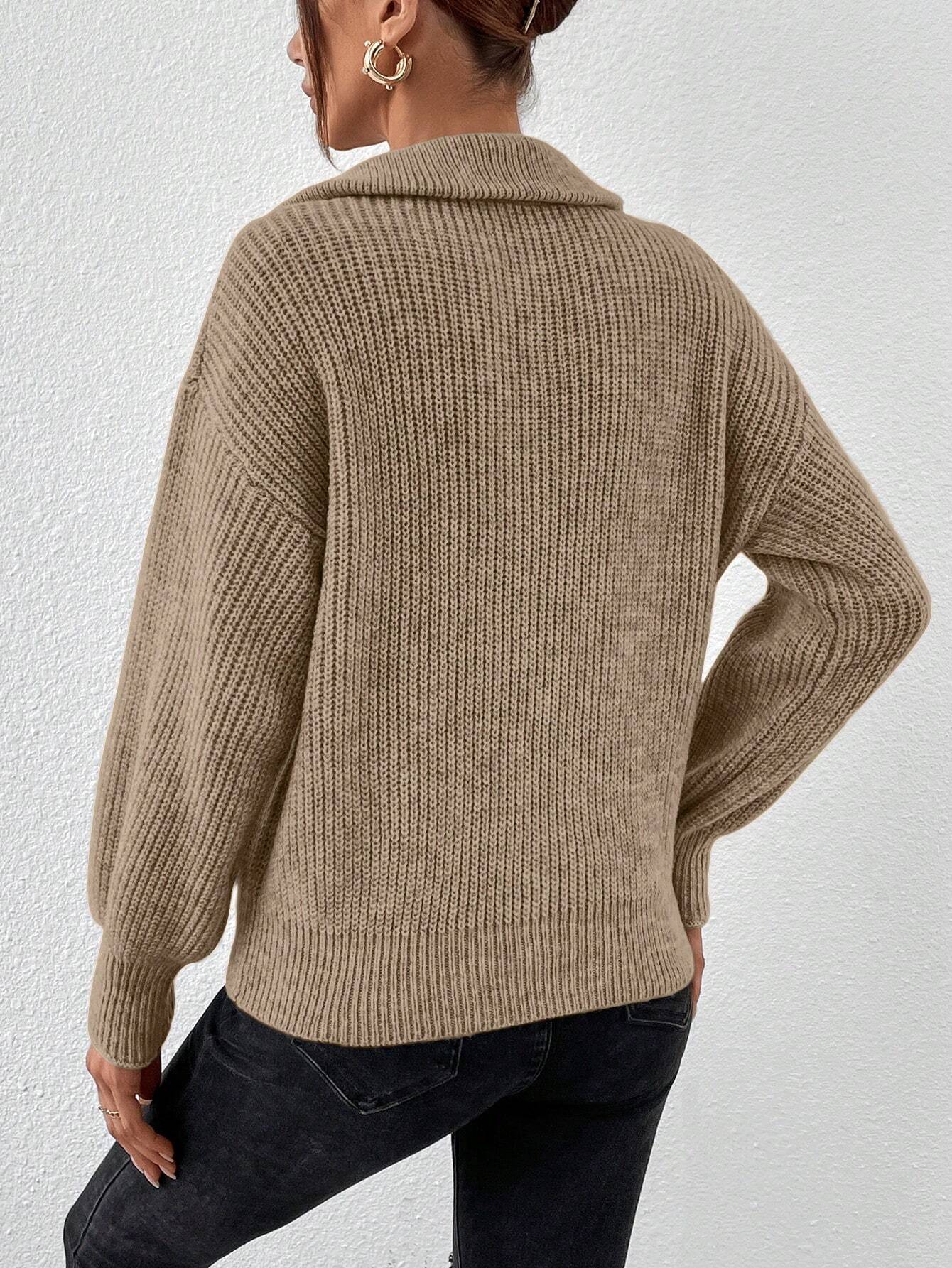 Person wearing a beige knitted sweater and black pants against a white background