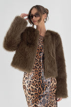 Woman wearing a brown fur coat over a leopard print dress on a white background