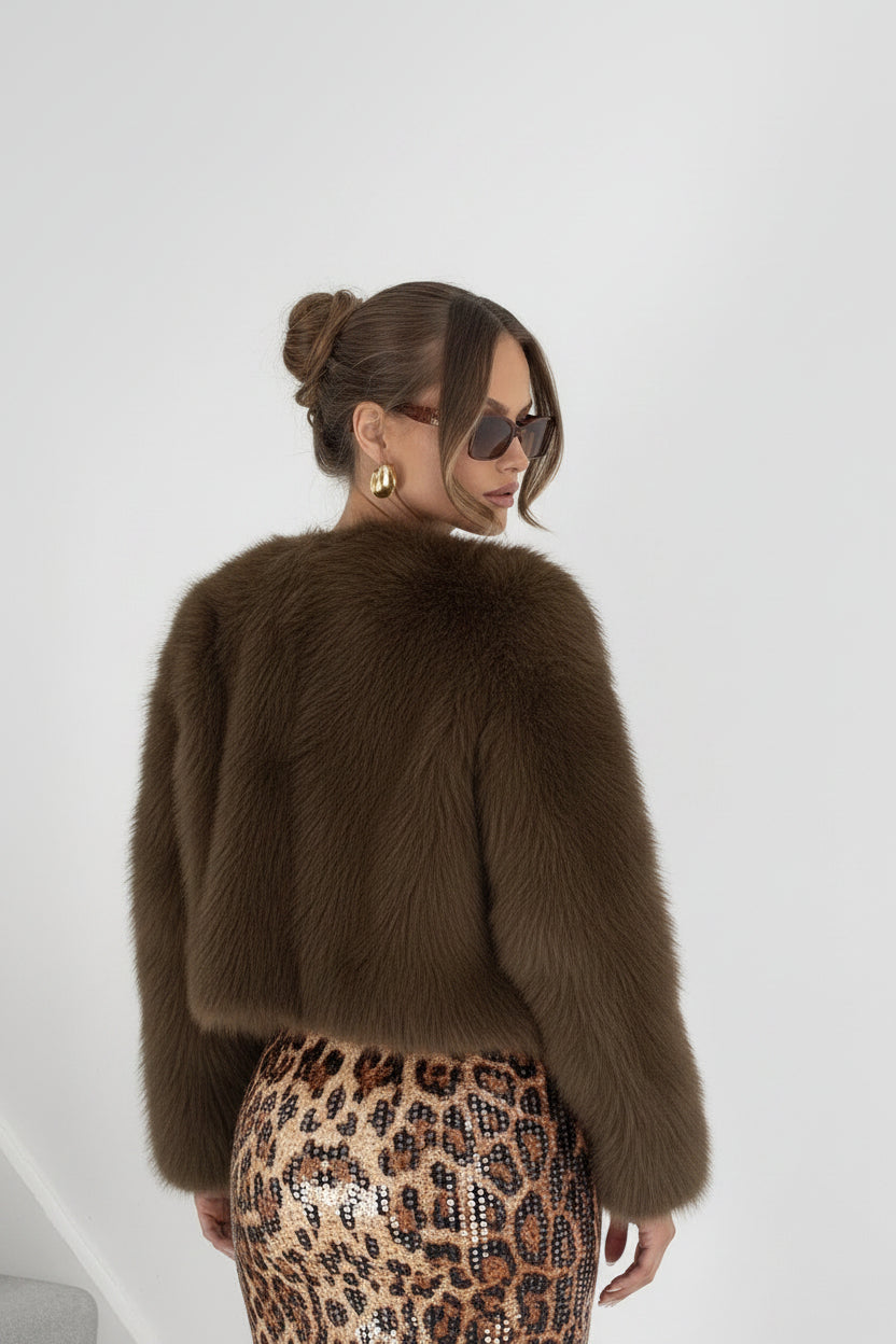 Woman wearing a brown fur coat and leopard print pants on a white background