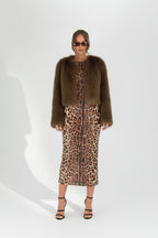 Woman wearing a brown fur coat over a leopard print dress against a white background