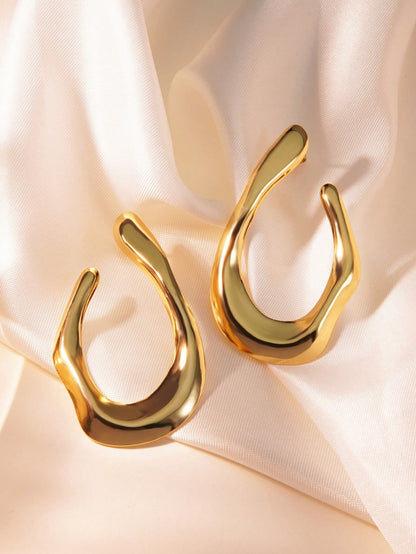 Gold U-shaped earrings on a soft pink fabric background