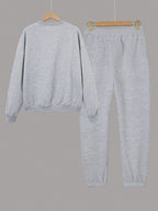 Gray sweatshirt and pants set on hangers against a gray background