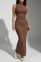 Woman wearing a brown sleeveless dress against a white background.