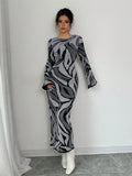 Woman wearing a patterned dress against a white wall