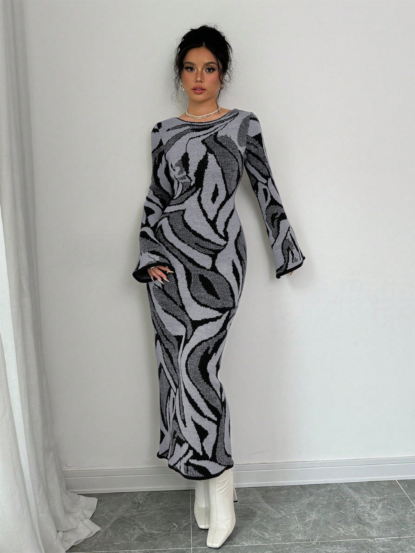 Woman wearing a patterned dress against a white wall