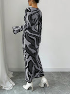 Person wearing a long, patterned dress with white shoes on a neutral background