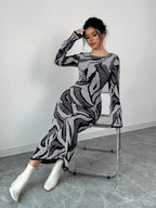 Woman sitting on a chair wearing a patterned outfit against a plain background
