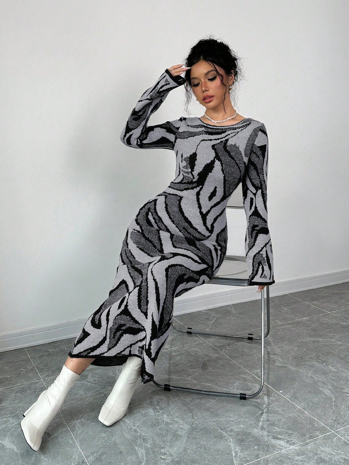 Woman sitting on a chair wearing a patterned outfit against a plain background
