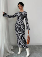 Woman wearing a patterned dress with white shoes and a brown bag, standing against a plain background.