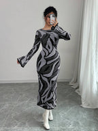 Person wearing a patterned dress in a room with a white curtain and gray floor.