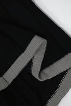 Close-up of a black sweater with gray ribbed trim on a white background