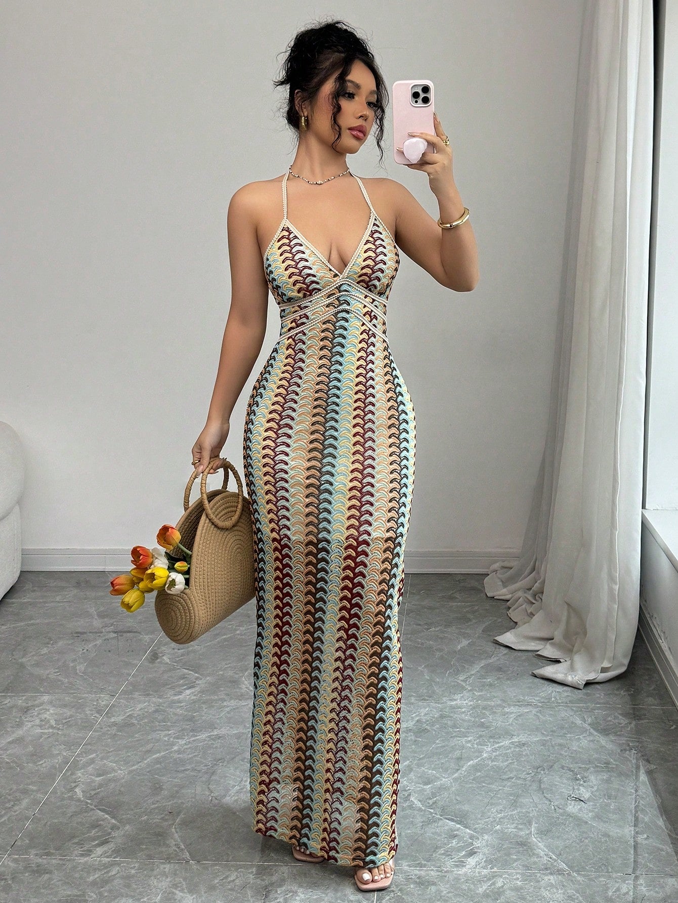 Woman in a patterned dress taking a mirror selfie in a room.