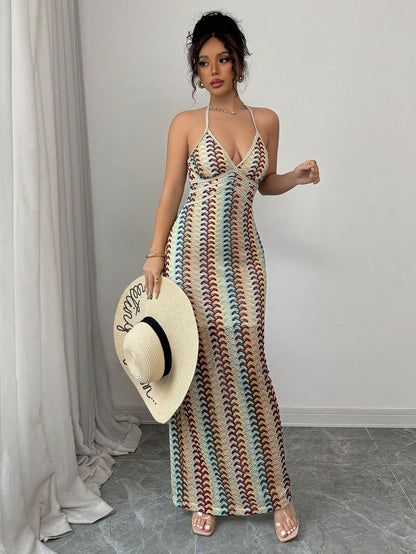 Woman wearing a colorful striped dress holding a hat indoors.
