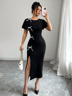 Woman in a black dress with white accents taking a mirror selfie.