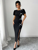 Woman wearing a black dress with white lace details against a white wall.