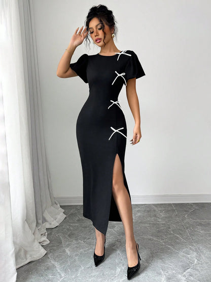 Woman wearing a black dress with white accents in a minimalistic setting