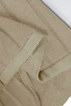 Close-up of a beige knitted sweater with a textured pattern.