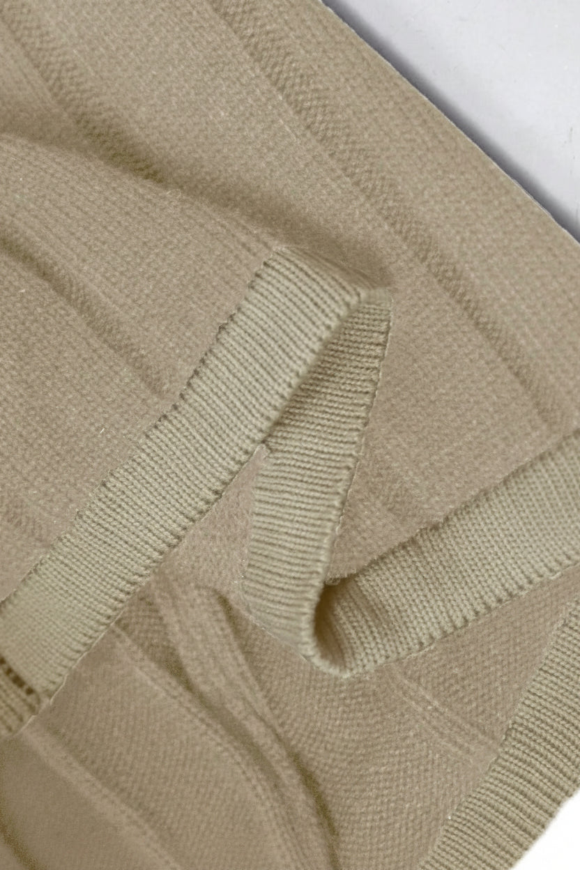 Close-up of a beige knitted sweater with a textured pattern.