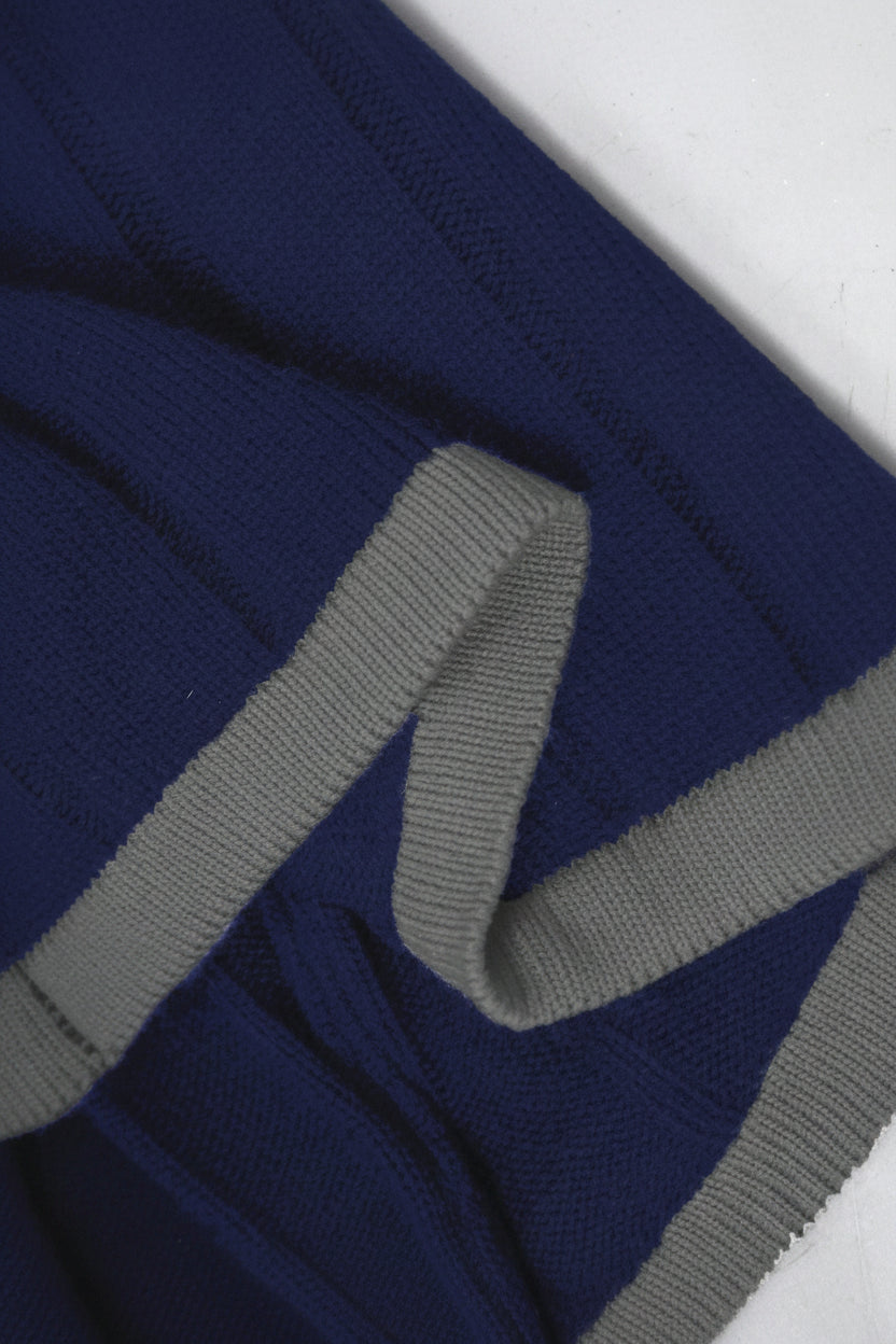 Close-up of a blue sweater with gray ribbed trim on a white background