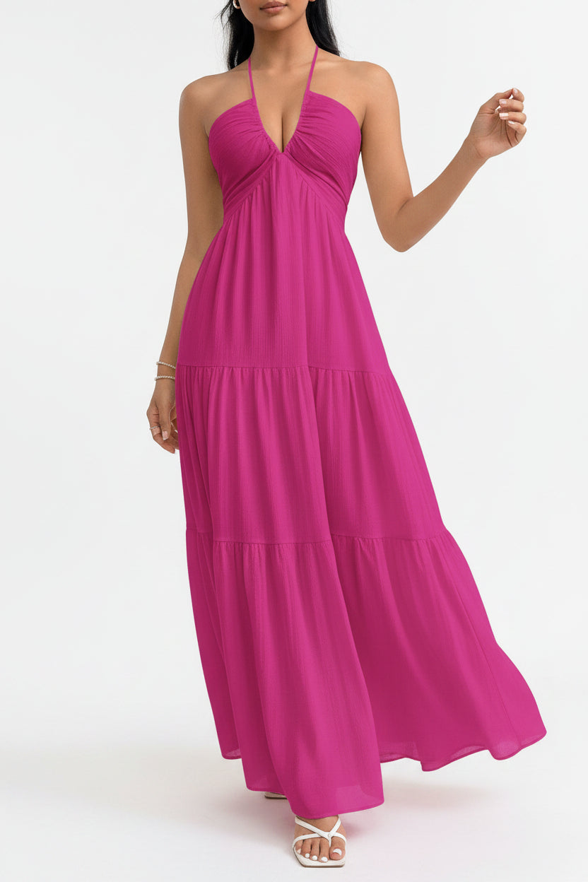 Woman wearing a pink halter neck dress against a white wall.