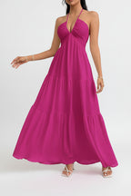 Woman wearing a pink halter neck dress on a gray background