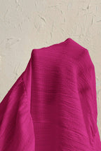 Close-up of a bright pink fabric against a beige background