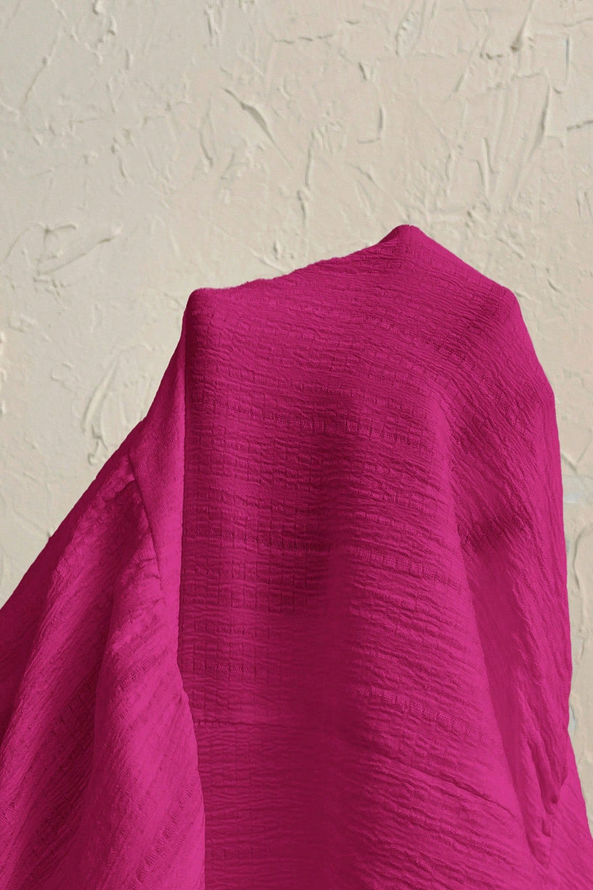 Close-up of a bright pink fabric against a beige background