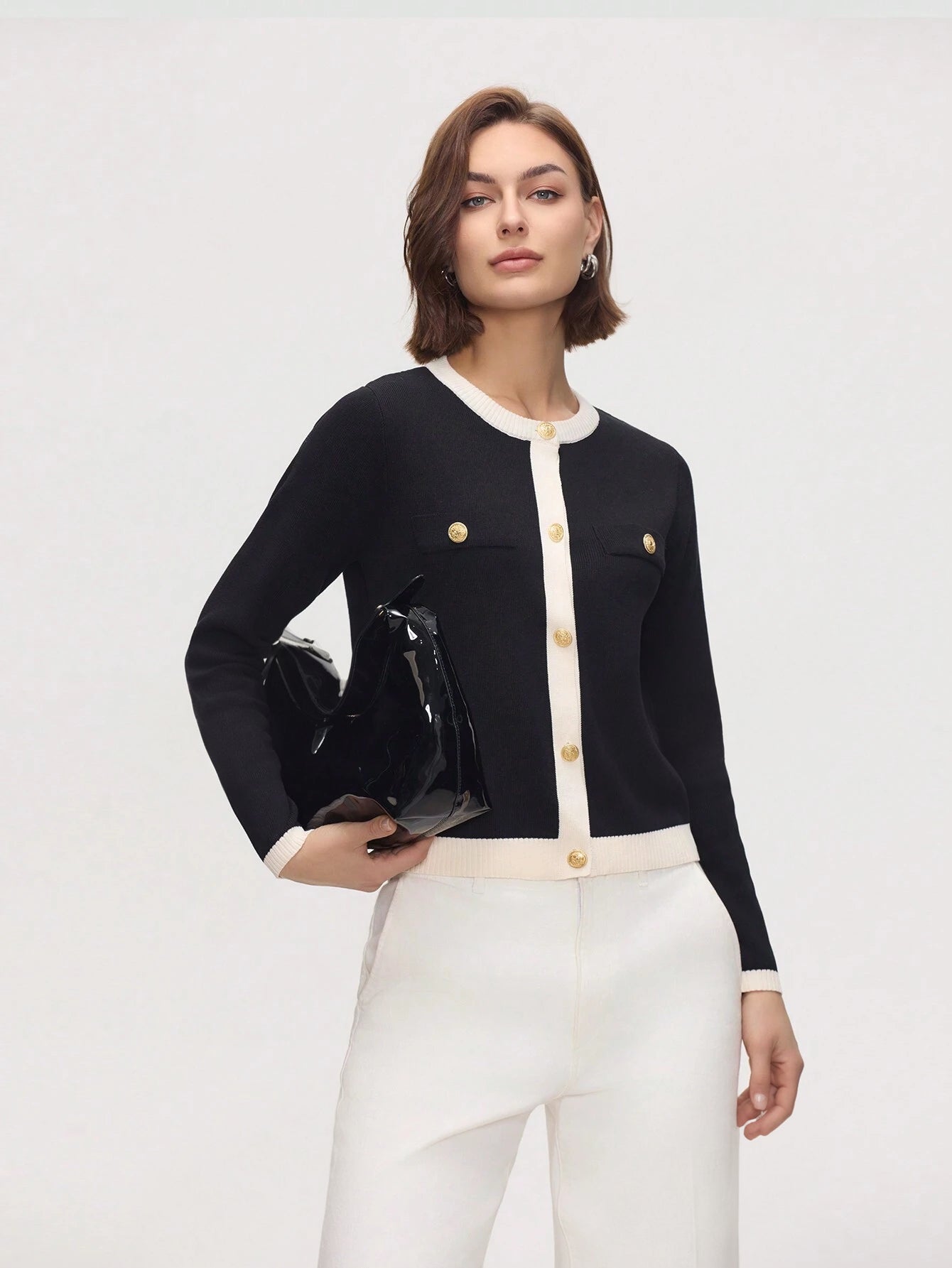 Woman wearing a black and white outfit with gold buttons on a white background